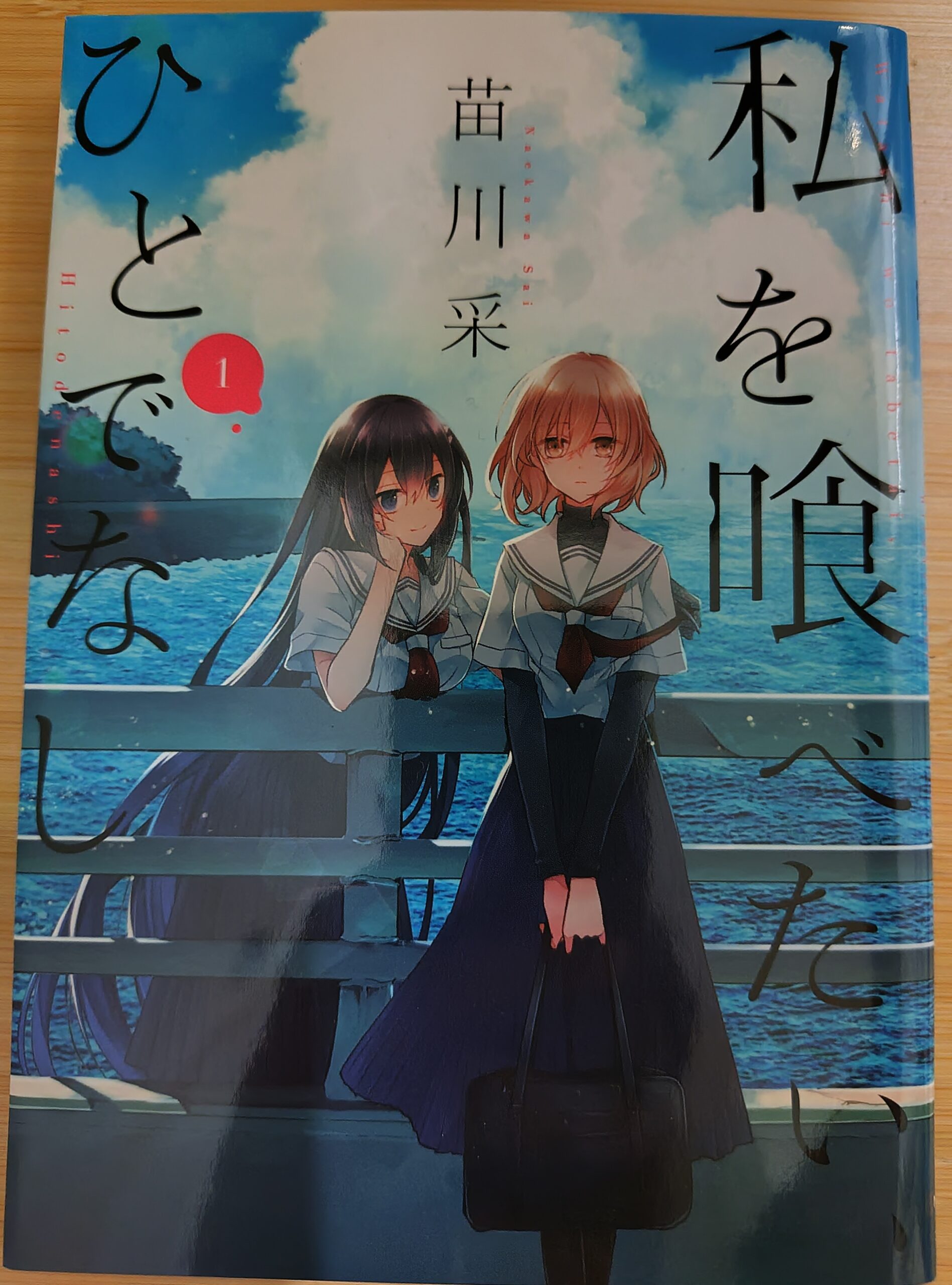 『私を喰べたいひとでなし』コミックス1巻の表紙。橋の上に立ちこちらを見ている比名子と汐莉。