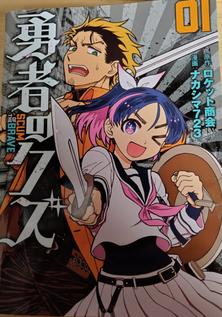 『勇者のクズ』1巻の表紙イラスト。青とピンクの髪をした女子高生・城ヶ峰亜希が剣と盾を構えてウインクし、背後には疲れた表情のヤシロが立っている。アクション性とキャラクター性が一目で伝わるデザイン。
