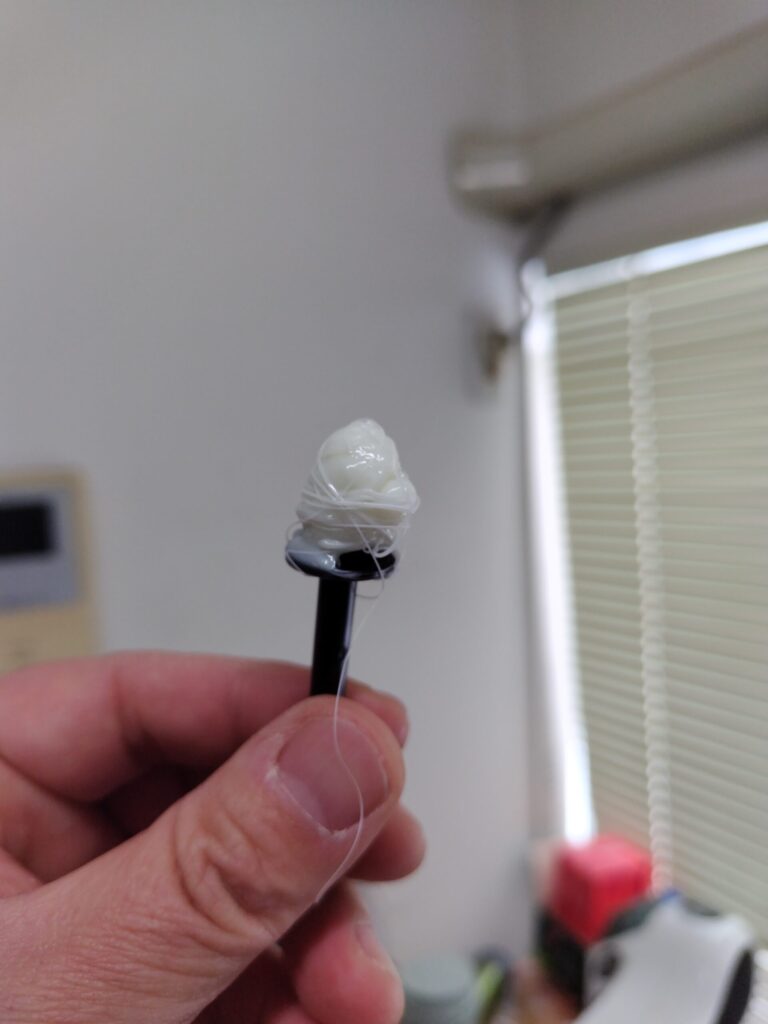 鼻毛用ワックスをつけたスティックを手に持っている様子。スティックに鼻毛用ワックスがまとわりついている。