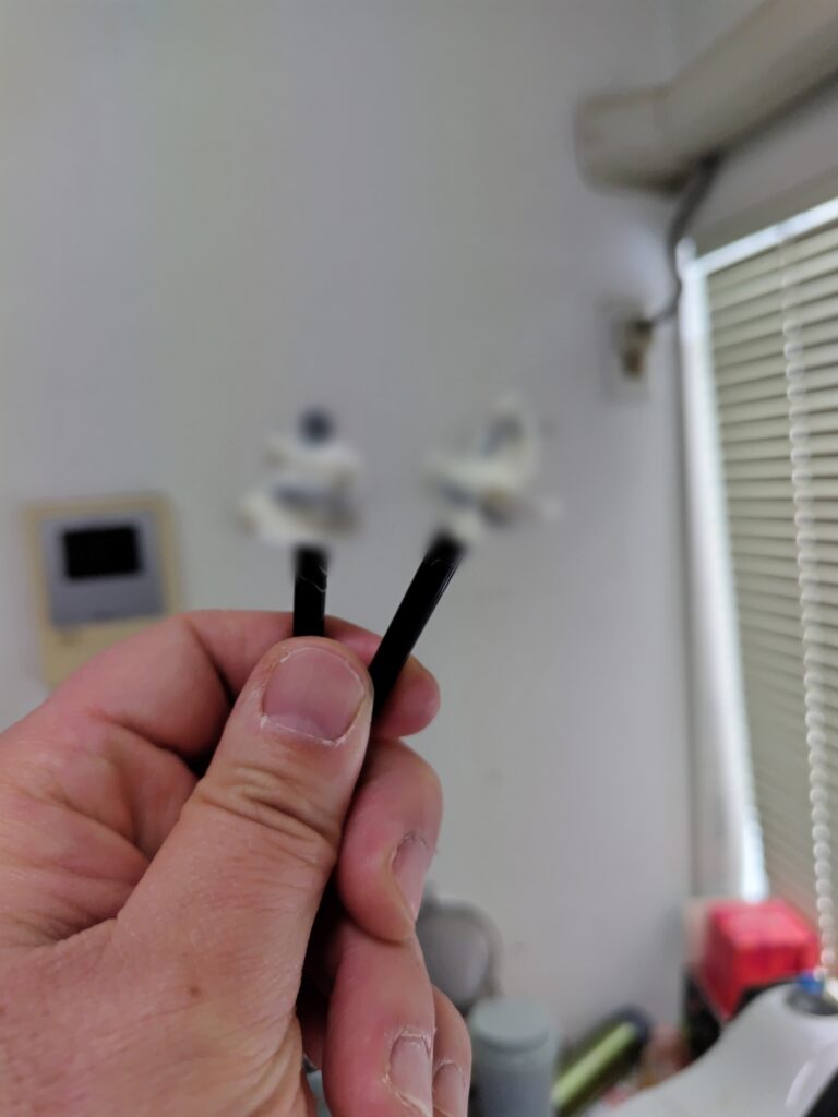 鼻毛用ワックスを使用した後のスティックを手に持っている様子。ワックスに抜けた鼻毛が付着しており、一部にモザイク加工が施されている。