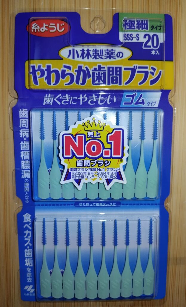 小林製薬のやわらか歯間ブラシ（ゴムタイプ）20本入りパッケージ。緑の持ち手と青いブラシが並び、SSS〜Sの極細サイズで歯ぐきに優しい設計。売上No.1の歯間ブラシとして、食べカスや歯垢を除去し歯周病予防に役立つことが強調されている。